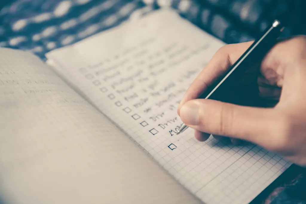 A hand ticking items on a checklist in a notebook