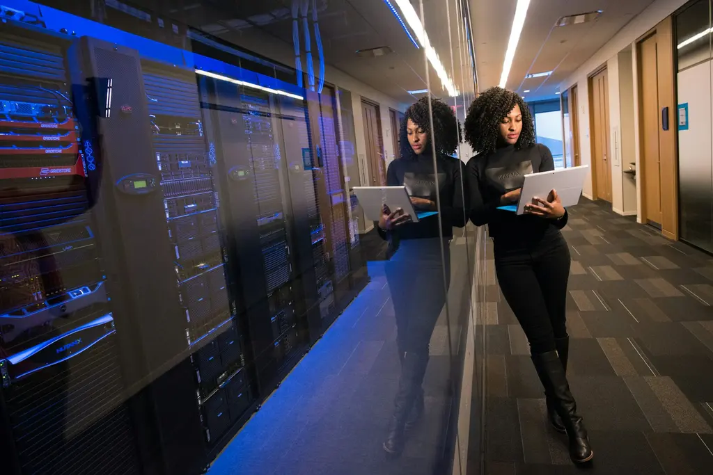 A technician with a laptop walking beside rows of server racks