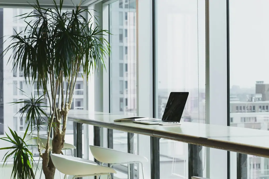 A bright, modern office with large windows, a desk and a laptop