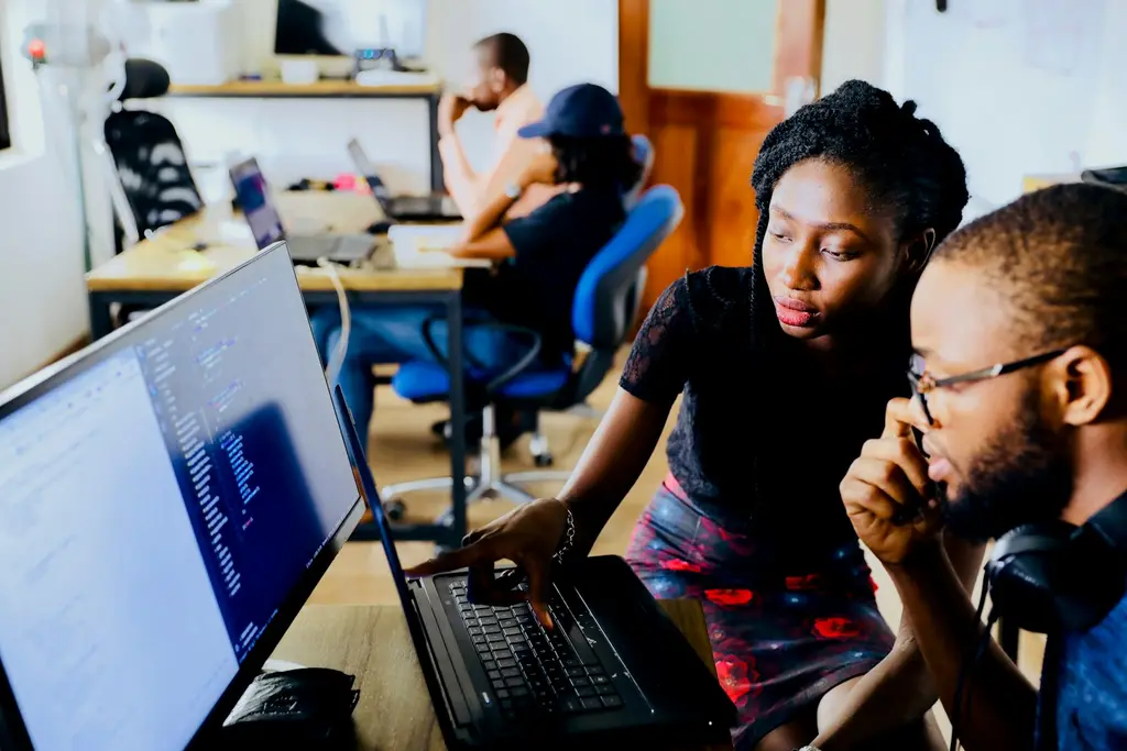 Two developers reviewing code together on a computer screen