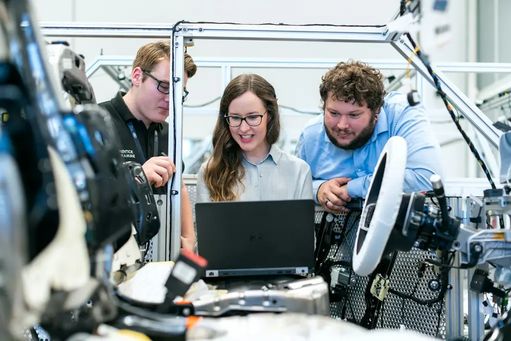 Three engineers reviewing data on a laptop beside equipment