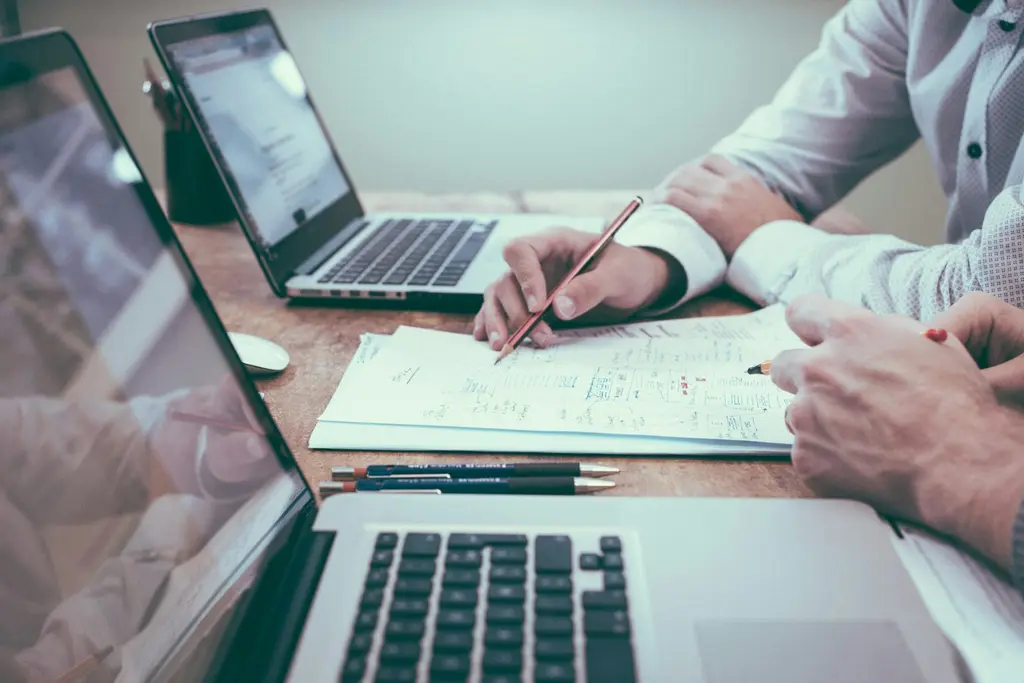 A professional reviewing financial paperwork beside a laptop