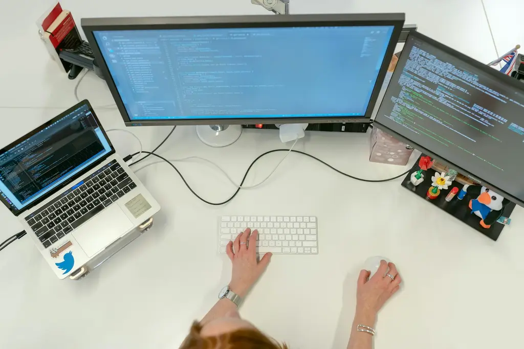 A developer working with code on two large monitors and a laptop