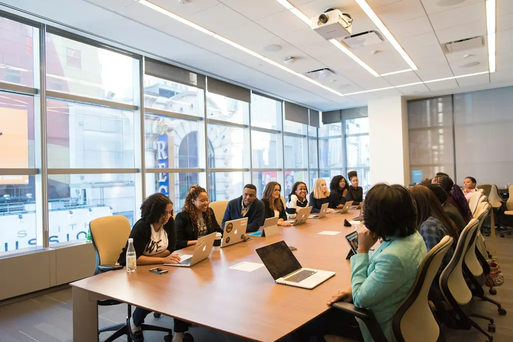A diverse group of professionals in a meeting around a long boardroom table