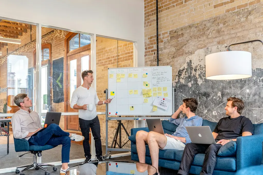 A team meeting in a modern office with a whiteboard covered in planning notes