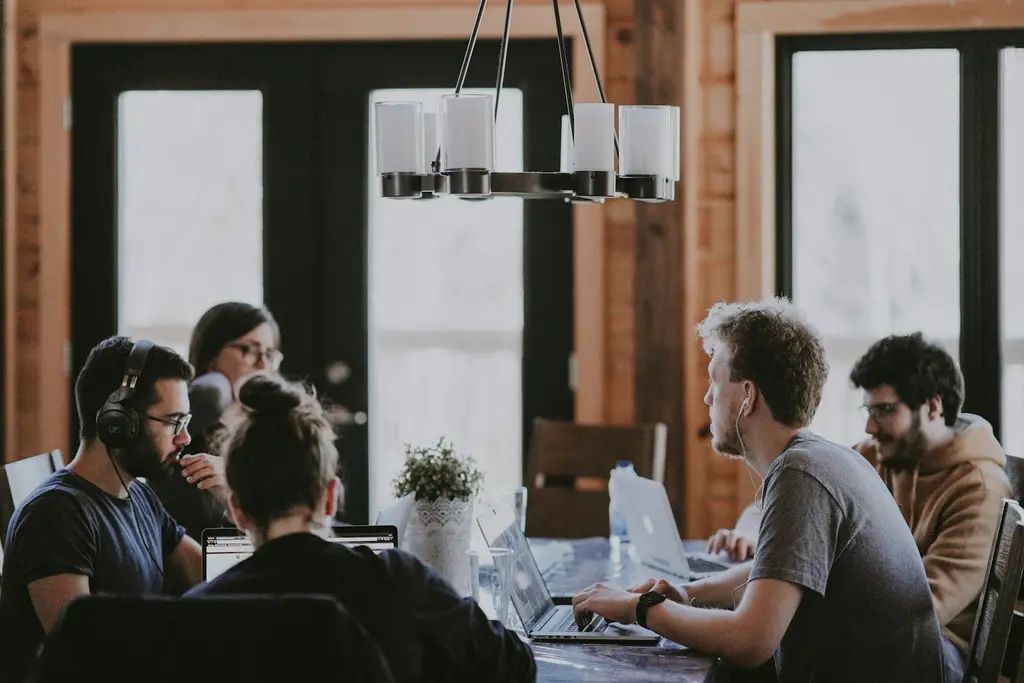 A team of colleagues working together around a table with laptops