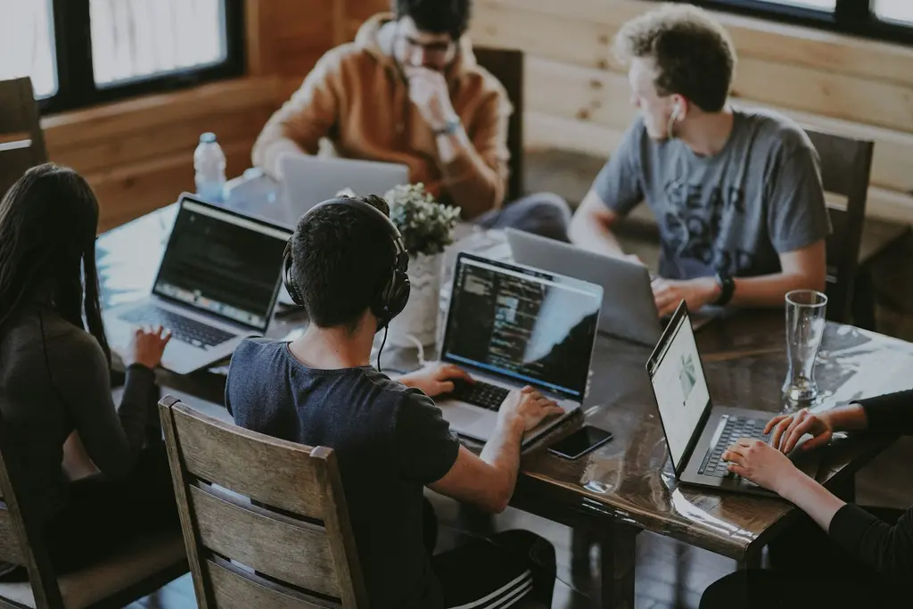 A team of developers working together on laptops around a shared table