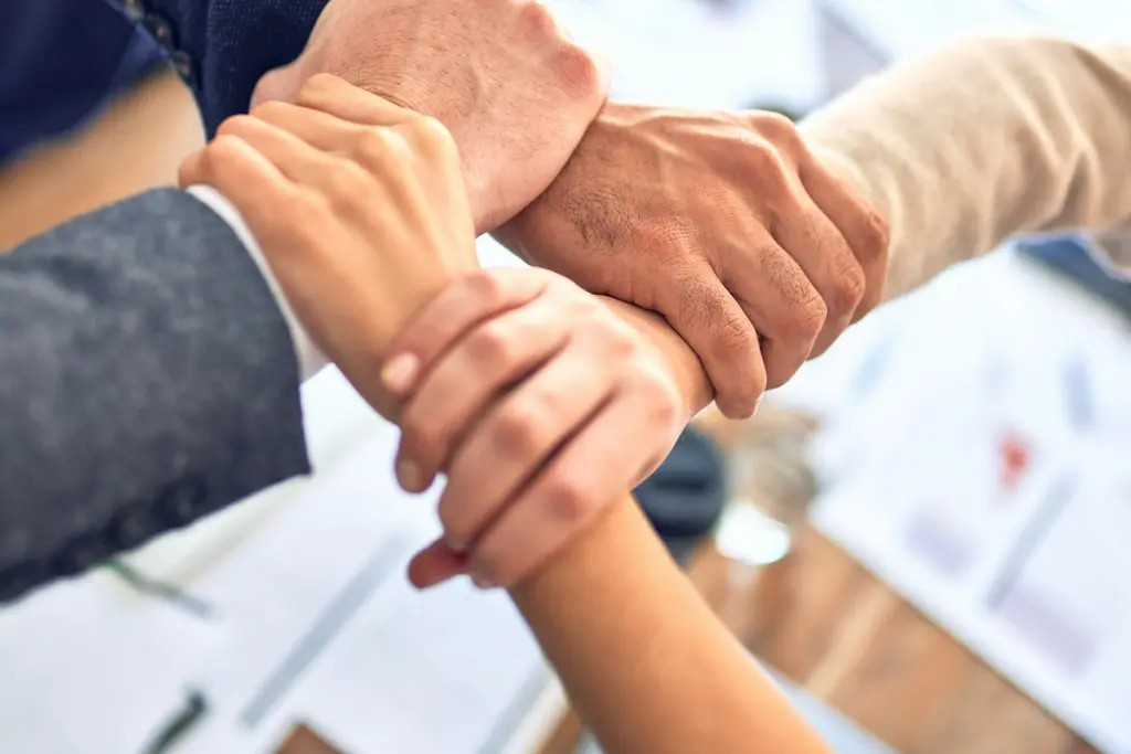 Colleagues joining hands in a show of teamwork