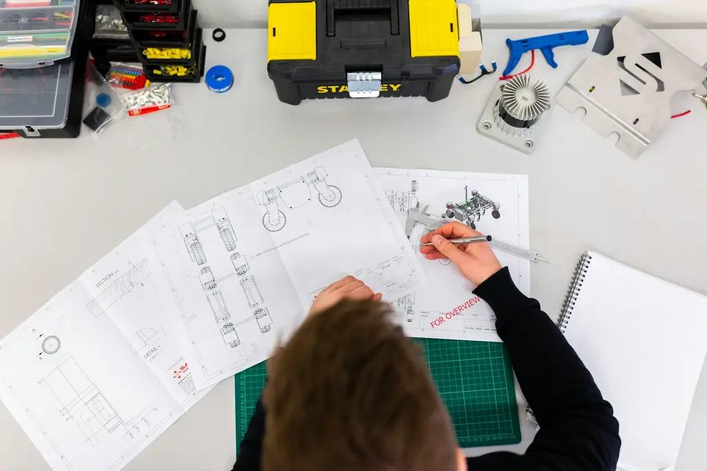 A technician working on detailed technical drawings at a desk